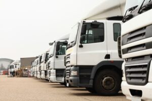 A cluster of white trucks rests in a parking lot, their vehicles neatly parked in formation.