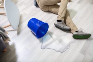 Accidents happen! Illustration of a mature man slipping on a wet floor caused by a spilled water bucket at home. Stay safe and prevent slips with proper precautions.